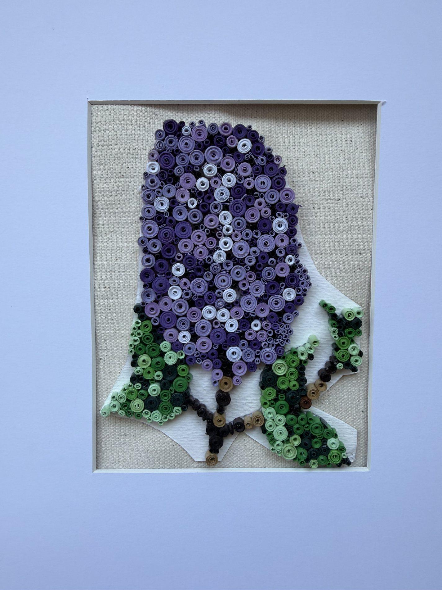 Purple whale quilling artwork surrounded by green paper plants