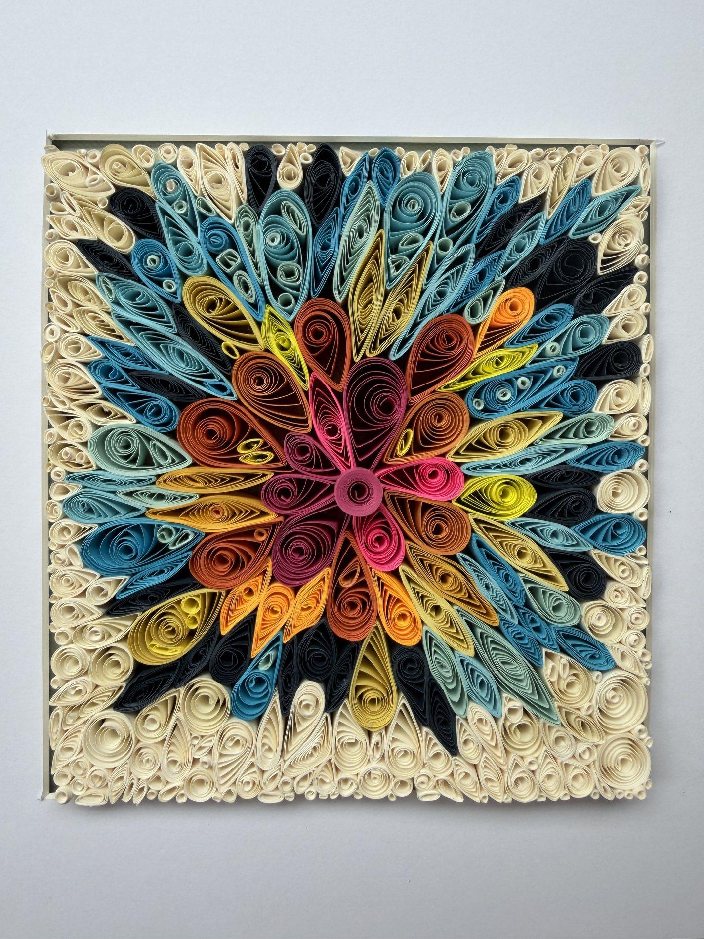 Radial flower quilling artwork in blue, pink, orange, yellow, black, and cream paper